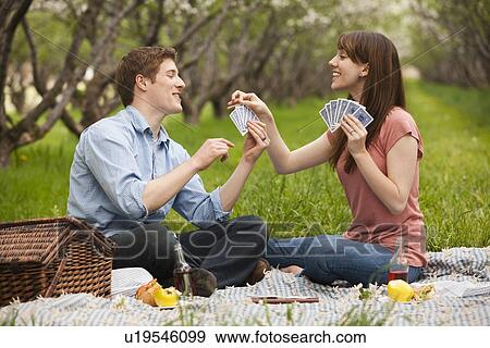 USA, Utah, Provo, Young couple playing cards during picnic in orchard View Large Photo Image Stock Photo - USA, Utah, Provo, Young couple playing cards during picnic in orchard. Fotosearch