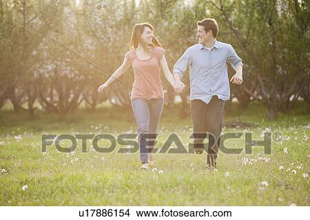 USA, Utah, Provo, Young couple running through orchard View Large Photo Image Picture - USA, Utah, Provo, Young couple running through orchard. Fotosearch