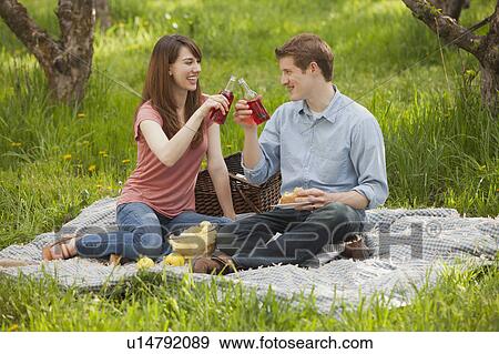 Stock Photo - USA, Utah, Provo, Young couple toasting drinks during picnic. Fotosearch