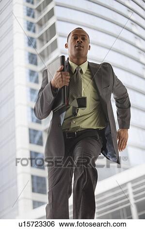 Stock Photograph - USA, Utah, Salt Lake City, Young businessman running in office building. Fotosearch