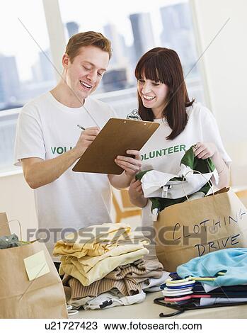 Stock Image - Volunteers organizing clothing drive. Fotosearch