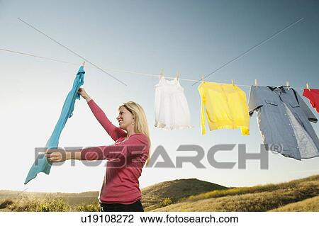Stock Image - Woman hanging laundry on clothesline . Fotosearch