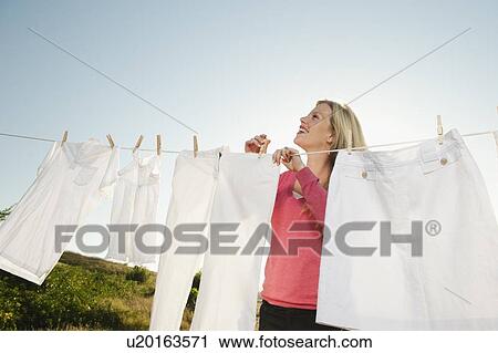 Woman hanging laundry on clothesline View Large Photo Image Stock Image - Woman hanging laundry on clothesline . Fotosearch