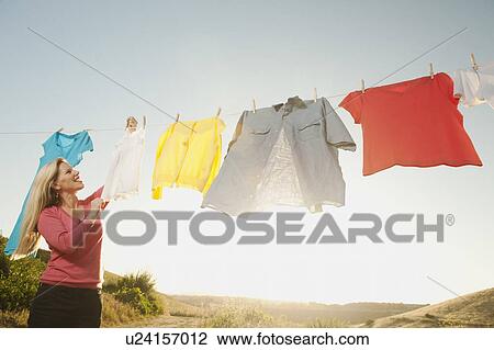 Stock Image - Woman hanging laundry on clothesline . Fotosearch
