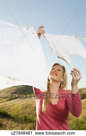 Stock Image - Woman hanging laundry on clothesline . Fotosearch