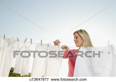 Woman hanging laundry on clothesline View Large Photo Image Stock Photo - Woman hanging laundry on clothesline . Fotosearch