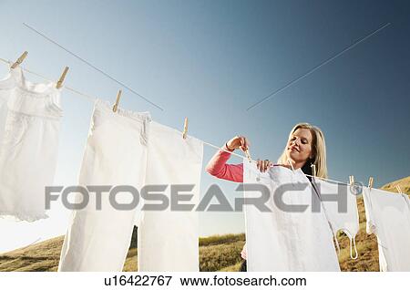 Stock Photo - Woman hanging laundry on clothesline . Fotosearch