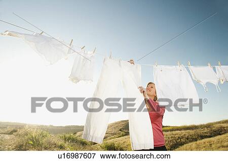 Stock Photo - Woman hanging laundry on clothesline . Fotosearch