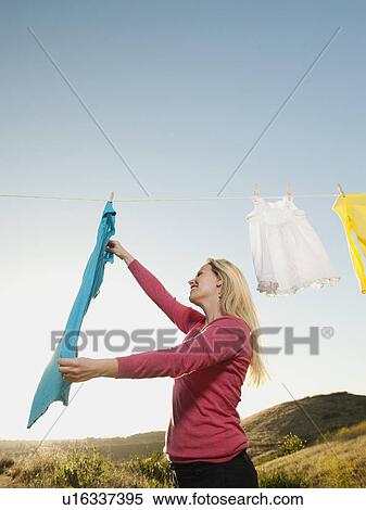 Stock Photography - Woman hanging laundry on clothesline . Fotosearch