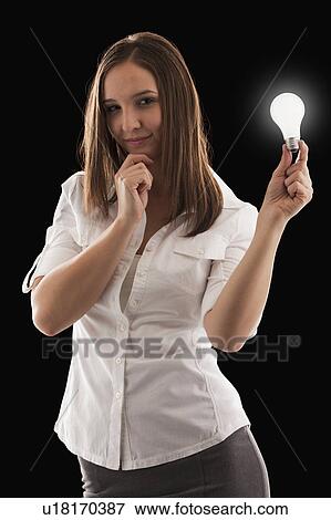 Young attractive businesswoman holding illuminated bulb View Large Photo Image Stock Photo - Young attractive businesswoman holding illuminated bulb. Fotosearch