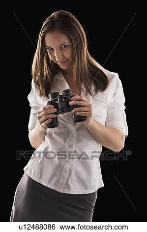 Stock Photograph - Young attractive businesswoman holding binoculars. Fotosearch