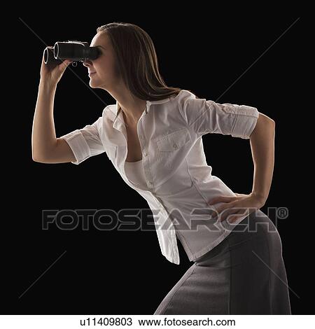 Stock Image - Young attractive businesswoman looking through binoculars. Fotosearch