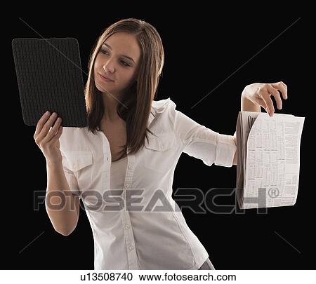 Stock Image - Young attractive businesswoman comparing financial results with financial column in newspaper. Fotosearch