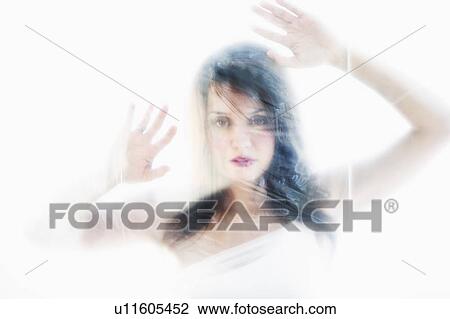 Stock Image - Young attractive woman looking from behind white sheet. Fotosearch