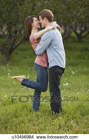 Picture - Young couple embracing in orchard. Fotosearch