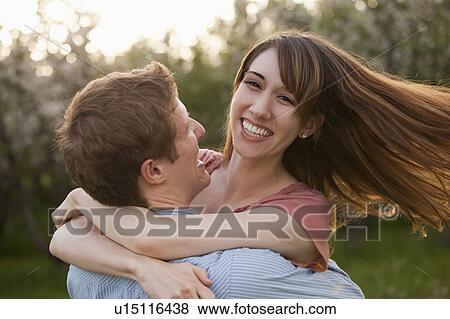Stock Photo - Young couple embracing in orchard. Fotosearch