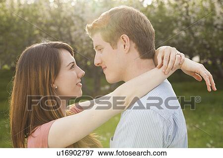 Stock Photo - Young couple embracing in orchard. Fotosearch