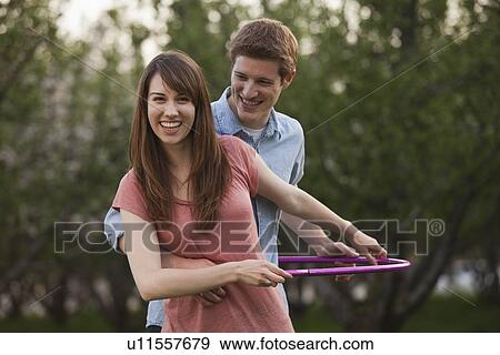 Young couple using plastic hoop in orchard View Large Photo Image Stock Photo - Young couple using plastic hoop in orchard. Fotosearch