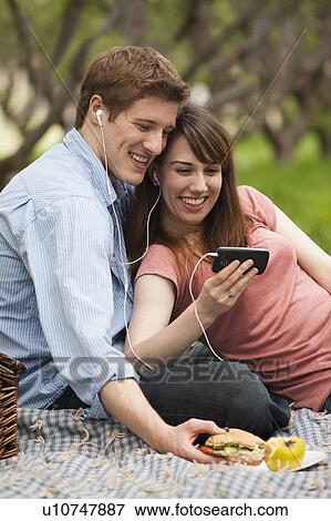 Young couple with mp3 player in orchard View Large Photo Image Stock Photo - Young couple with mp3 player in orchard. Fotosearch