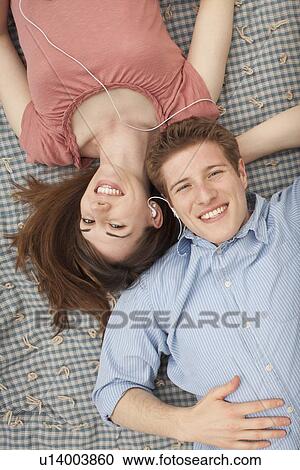 Young couple with mp3 player lying on blanket View Large Photo Image Stock Image - Young couple with mp3 player lying on blanket. Fotosearch