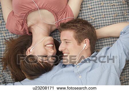 Stock Image - Young couple with mp3 player lying on blanket. Fotosearch