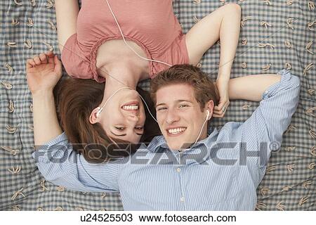 Stock Image - Young couple with mp3 player lying on blanket. Fotosearch