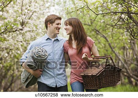 Stock Photo - Young couple with picnic basket in orchard. Fotosearch
