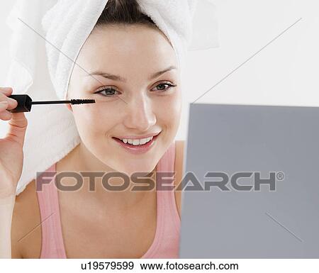 Stock Photo - Young woman applying mascara. Fotosearch