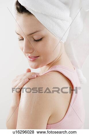 Young woman applying moisturizer on shoulder View Large Photo Image Stock Photo - Young woman applying moisturizer on shoulder. Fotosearch