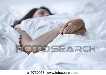 Stock Image - Young woman daydreaming in bed. Fotosearch