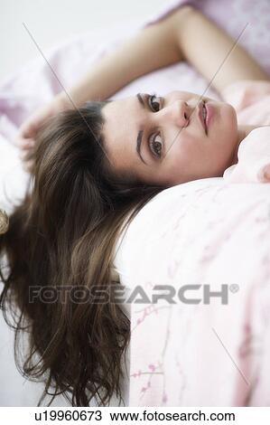 Stock Image - Young woman daydreaming in bed. Fotosearch