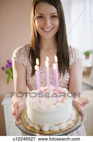 Stock Photo - Young woman holding birthday cake. Fotosearch