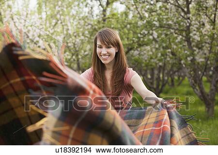 Young woman holding blanket in orchard View Large Photo Image Picture - Young woman holding blanket in orchard. Fotosearch