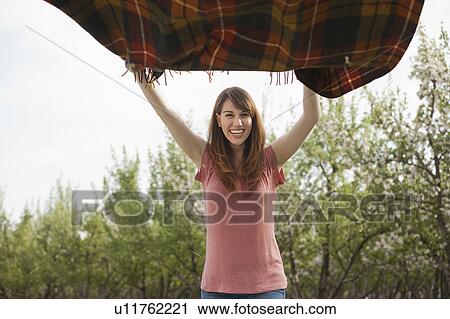 Young woman holding blanket in orchard View Large Photo Image Stock Image - Young woman holding blanket in orchard. Fotosearch