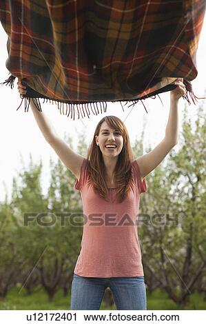 Young woman holding blanket in orchard View Large Photo Image Stock Image - Young woman holding blanket in orchard. Fotosearch