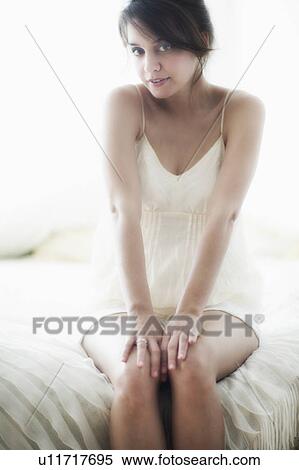 Young woman in nightwear sitting on bed View Large Photo Image Stock Photography - Young woman in nightwear sitting on bed. Fotosearch