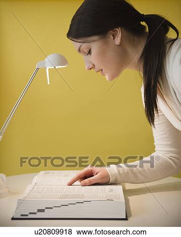 Young woman looking at dictionary View Large Photo Image Stock Photo - Young woman looking at dictionary. Fotosearch