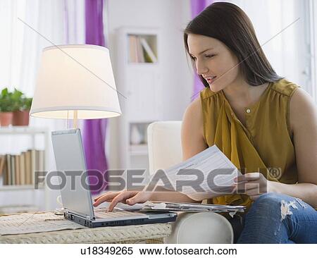 Stock Photography - Young woman paying bills on line. Fotosearch