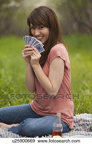 Stock Photo - Young woman playing cards in orchard. Fotosearch