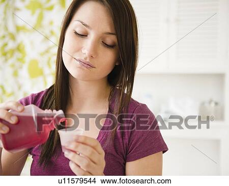 Picture - Young woman pouring syrup into measuring cup. Fotosearch