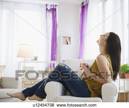 Young woman sitting on armchair with champagne flute View Large Photo Image Stock Photo - Young woman sitting on armchair with champagne flute. Fotosearch