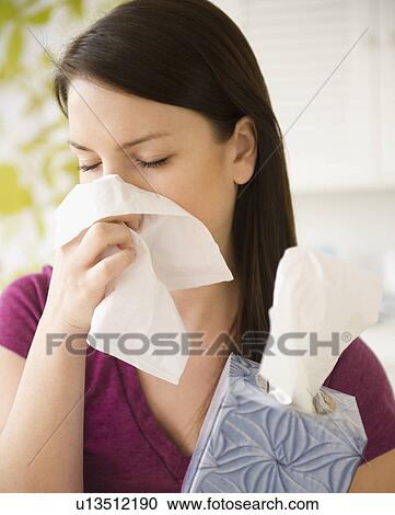 Young woman sneezing into tissue View Large Photo Image Stock Image - Young woman sneezing into tissue. Fotosearch