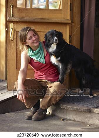 Stock Photo - Young woman with dog sitting on porch. Fotosearch