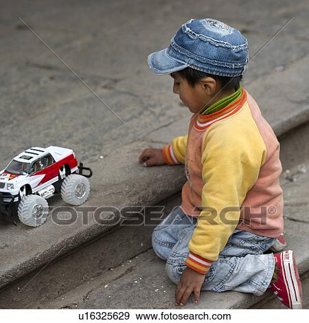Stock Photo - Boy playing with a toy car, Cuzco, Peru. Fotosearch