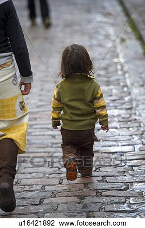 Stock Image - Child walking with mother on a cobblestone walkway, Cuzco, Peru. Fotosearch