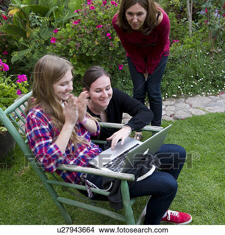 Family looking at a laptop in the lawn of Willka Tika Guesthouse, Willka Tika, Sacred Valley, Cusco Region, Peru View Large Photo Image Picture - Family looking at a laptop in the lawn of Willka Tika Guesthouse, Willka Tika, Sacred Valley, Cusco Region, Peru. Fotosearch