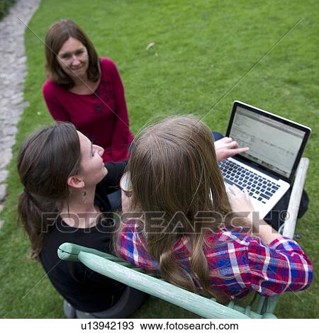Stock Image - Family looking at a laptop in the lawn of Willka Tika Guesthouse, Willka Tika, Sacred Valley, Cusco Region, Peru. Fotosearch
