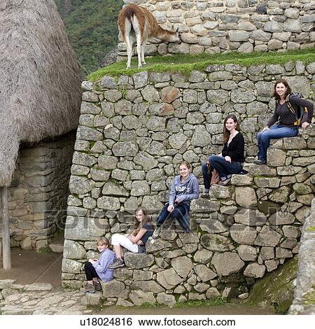 Stock Photograph - Friends sitting on a staircase at The Lost City of The Incas, Machu Picchu, Cusco Region, Peru. Fotosearch