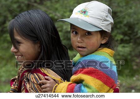 Picture - Girl giving piggyback to her sister and smiling, Sacred Valley, Cusco Region, Peru. Fotosearch