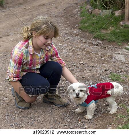Stock Image - Girl playing with a puppy dog, Sacred Valley, Cusco Region, Peru. Fotosearch